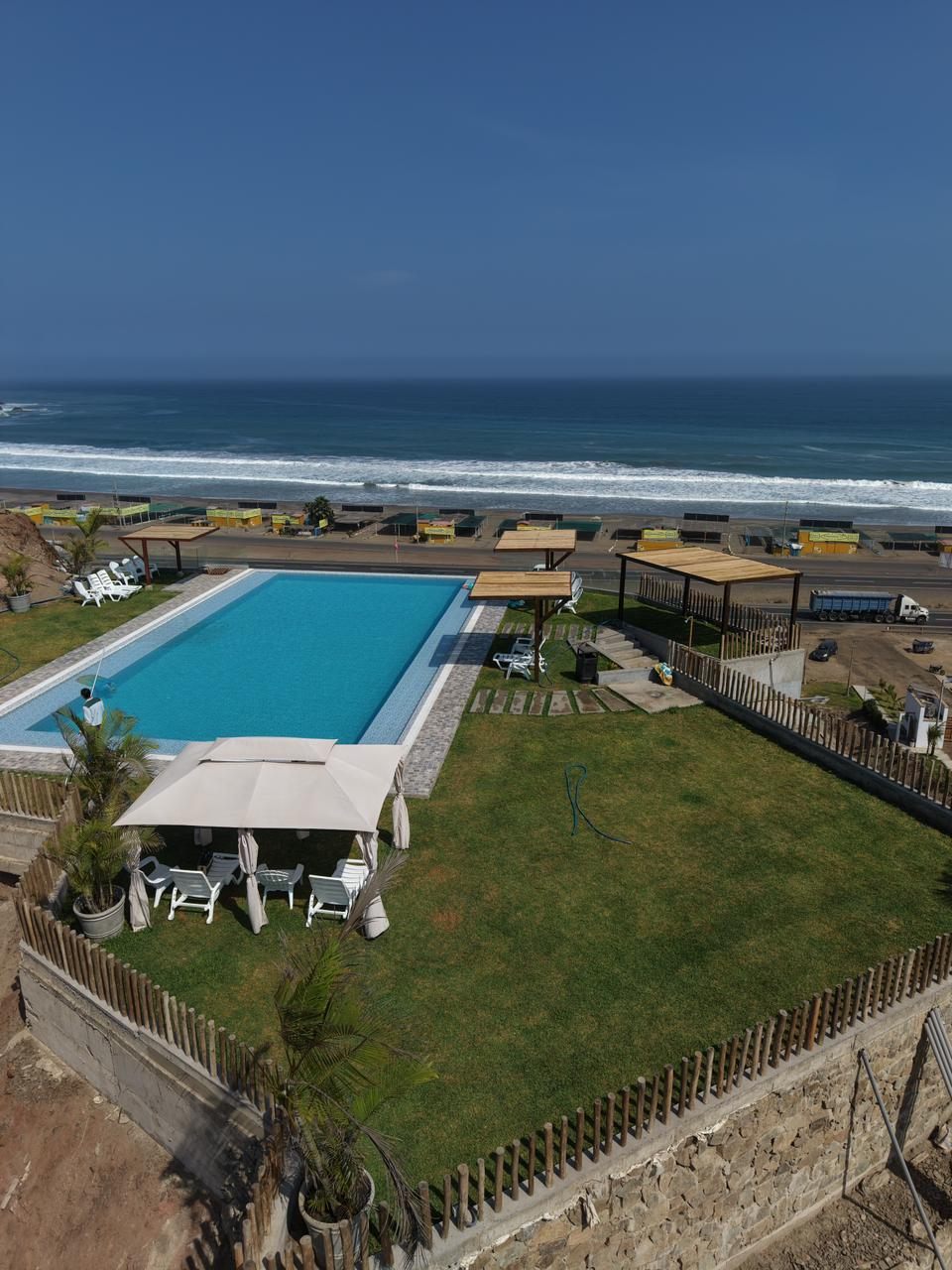 Piscina del condominio con terraza, toldos y el mar al fondo